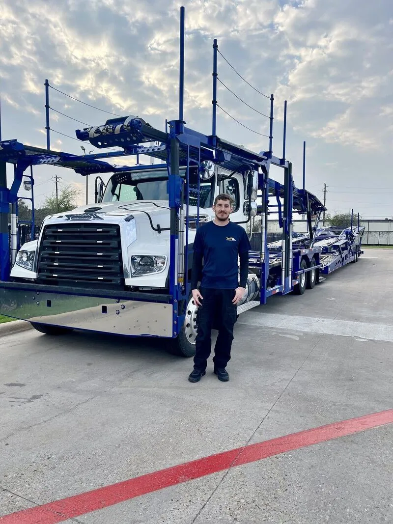 A driver standing beside his car carrier